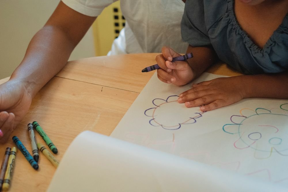 A parent and child drawing together at a table